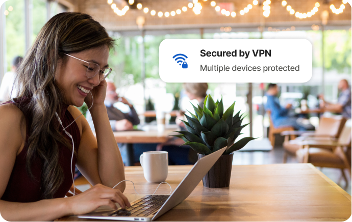 Kobieta w kawiarni uśmiechająca się do ekranu laptopa