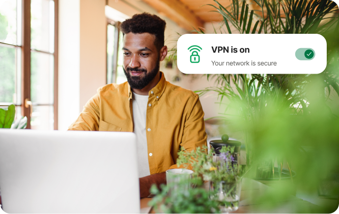 Mężczyzna otoczony roślinami, uśmiechający się w stronę laptopa